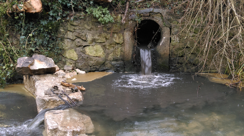 Sewage flowing out of a drain into a river